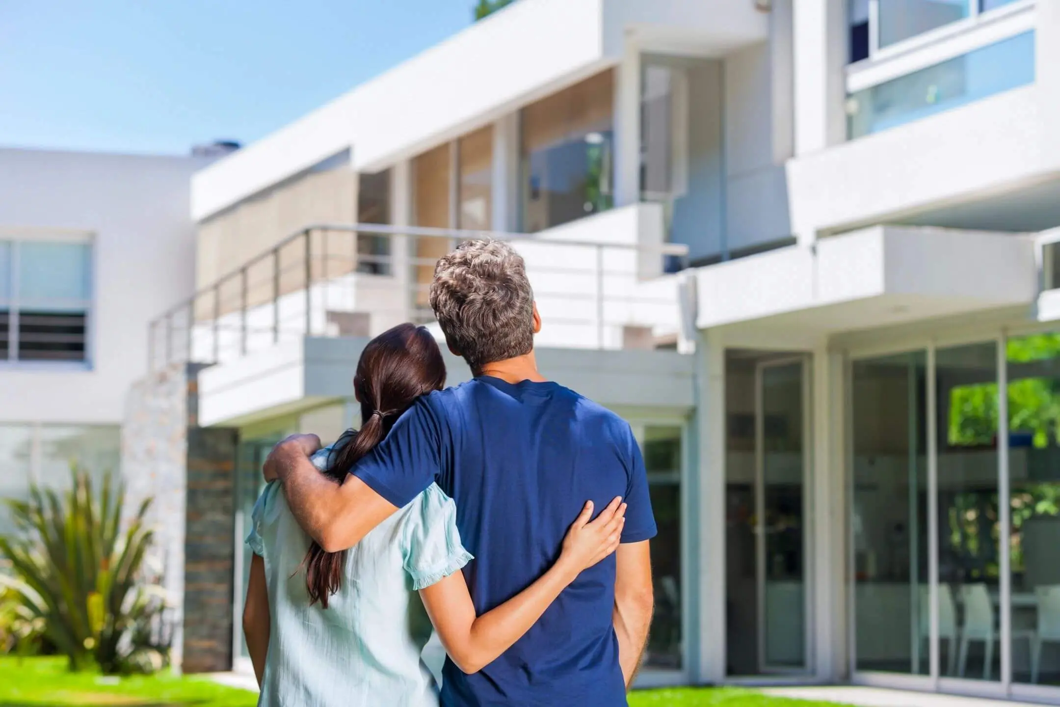 A couple embraces while looking at a modern house.