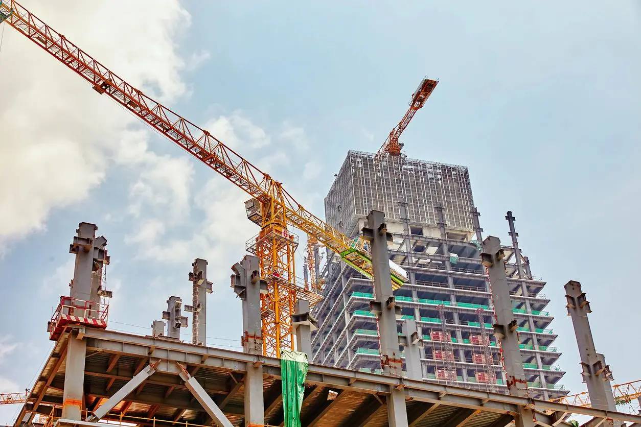 Construction site with cranes and a high-rise building under development.