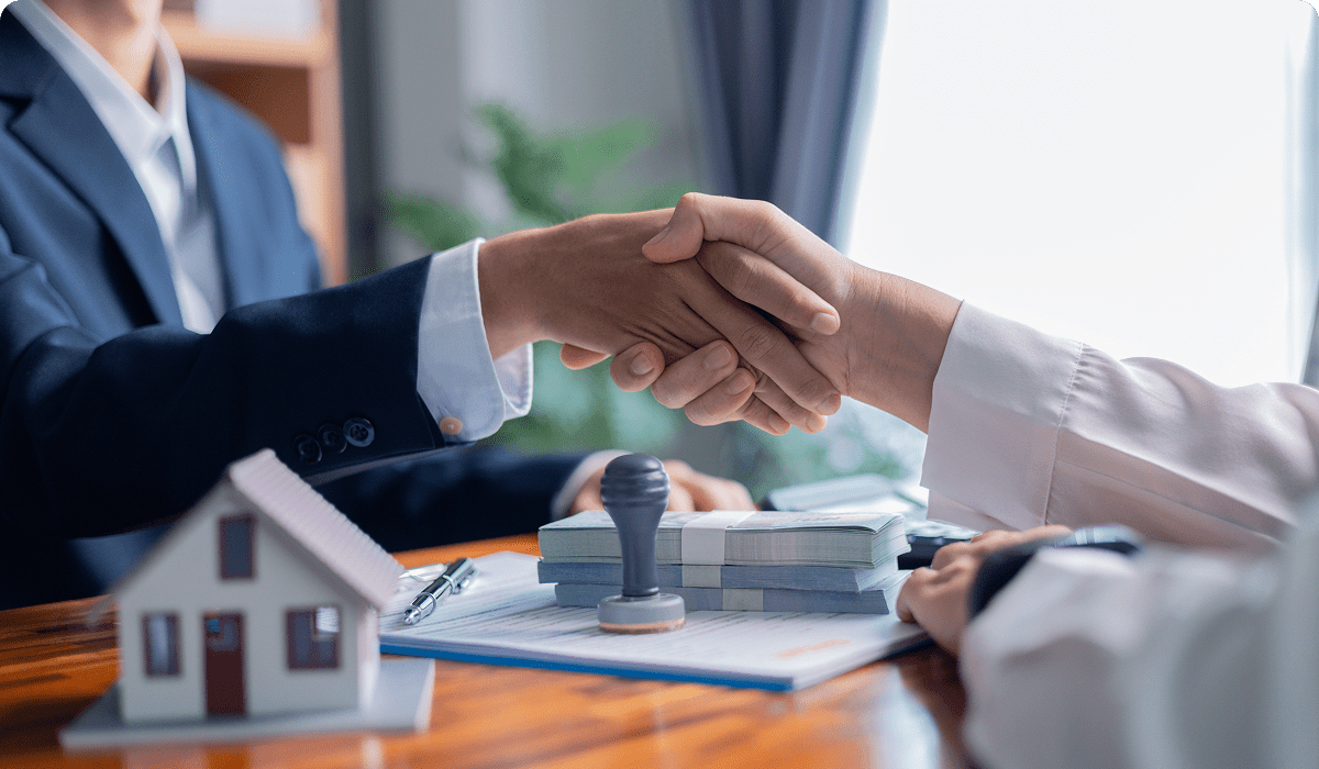 Handshake over real estate contract and model.