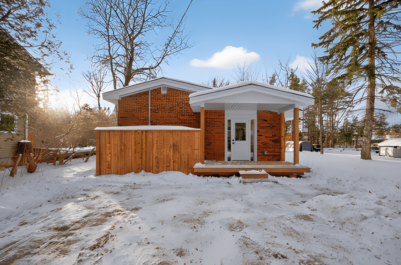 Cozy brick house with wooden deck in snowy yard.